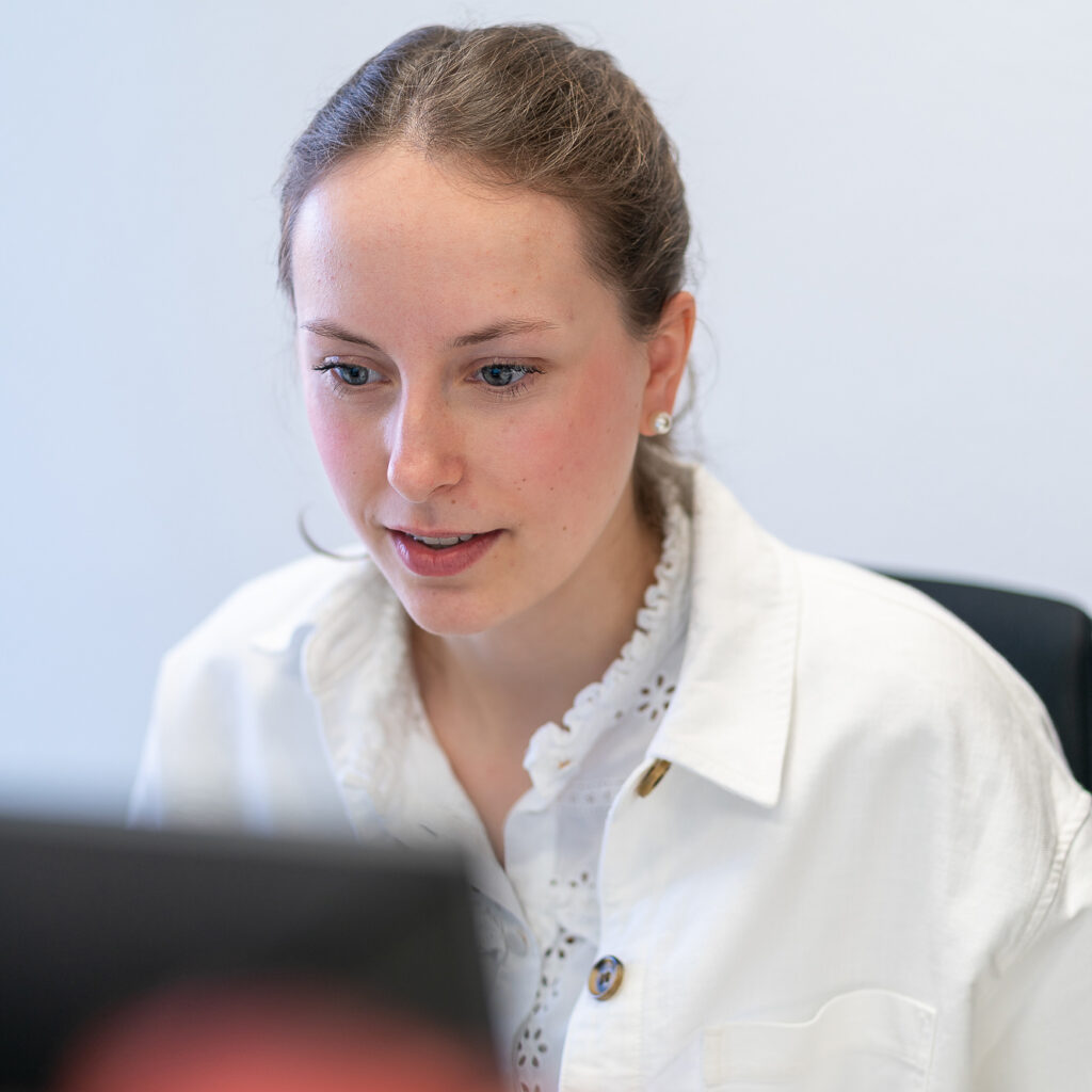 Mitarbeiterin der Steuerkanzlei sitzt konzentriert an ihrem Computer und bearbeitet digitale Unterlagen an einem hellen Arbeitsplatz.