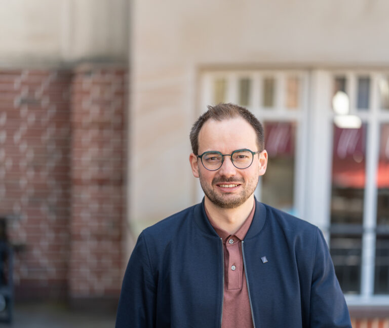 Jörg Pöttker, Partner von Meyer, Beelmann & Partner, lächelt in einem Porträt vor einem modernen Bürogebäude in die Kamera