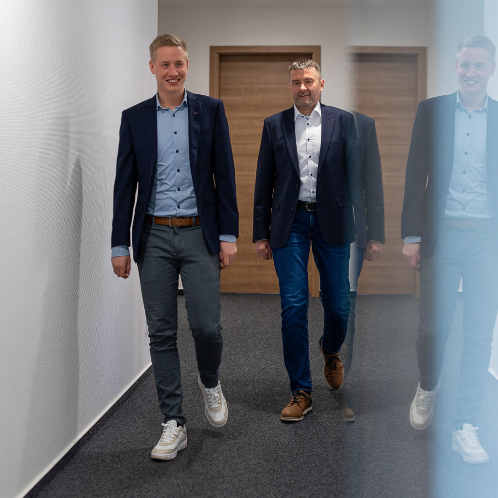 Zwei Partner der Steuerkanzlei gehen gemeinsam durch einen hellen Flur.